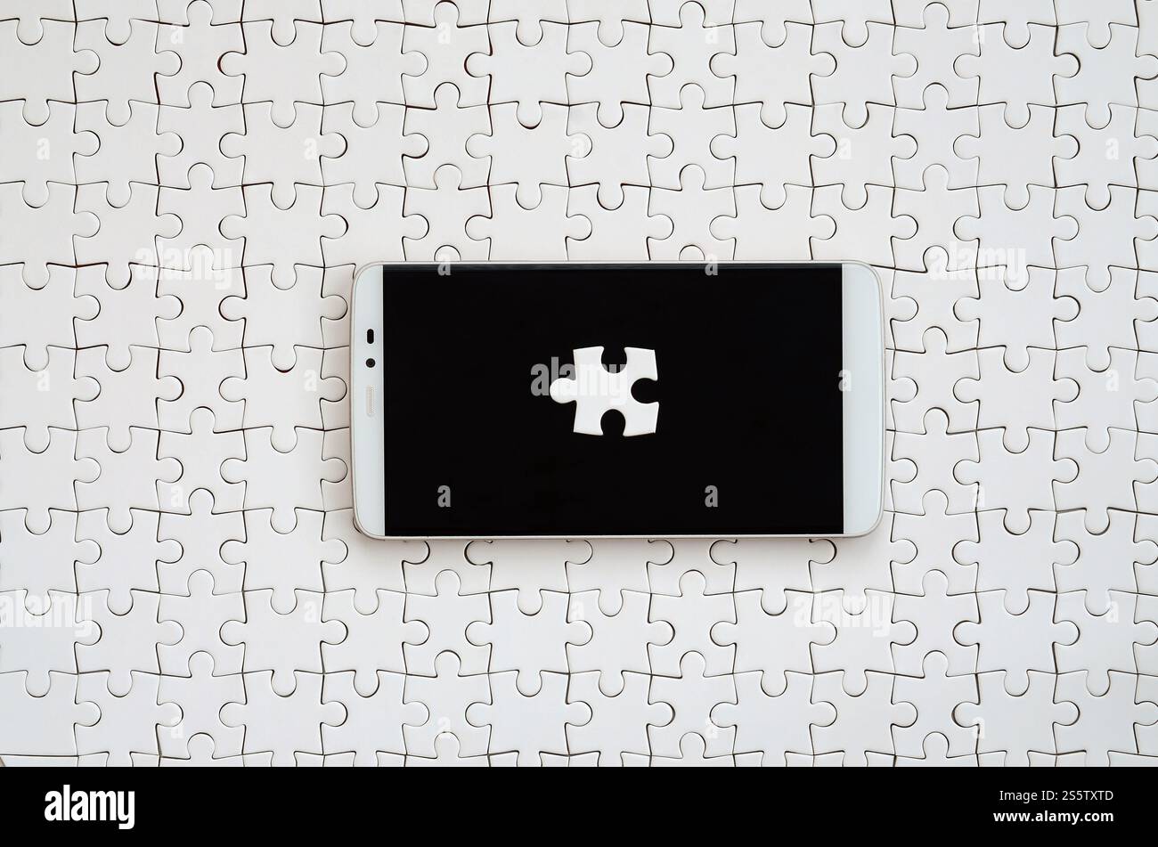 Eine moderne grosse Smartphone mit mehreren puzzle Elemente auf dem Touchscreen liegt auf einem weißen Puzzle im zusammengebauten Zustand Stockfoto
