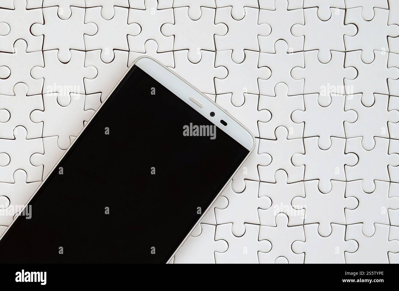 Eine moderne grosse Smartphone mit Touchscreen liegt auf einem weißen Puzzle im zusammengebauten Zustand Stockfoto