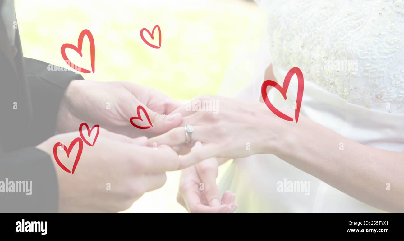 Bild von roten Herzen über kaukasischem Paar, das Ringe trägt Stockfoto