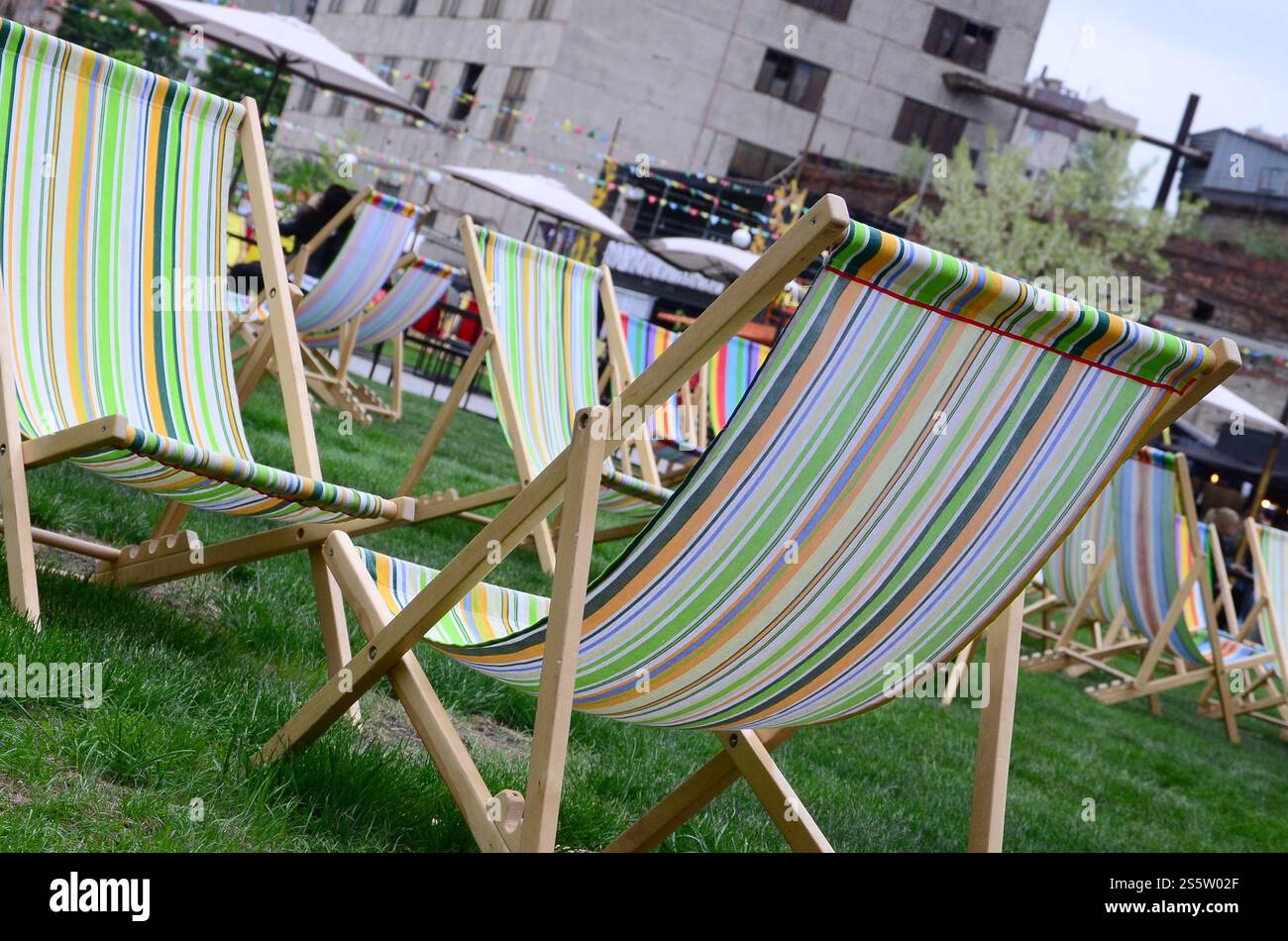 Liegestühle auf einem Rasen. Ruhen Sie sich auf dem Festival aus, im Urlaub. Gartenliegen auf grünem Gras. Gartenbett zum Sonnenbaden und Ausruhen. Sommerstuhl. Chaise Stockfoto