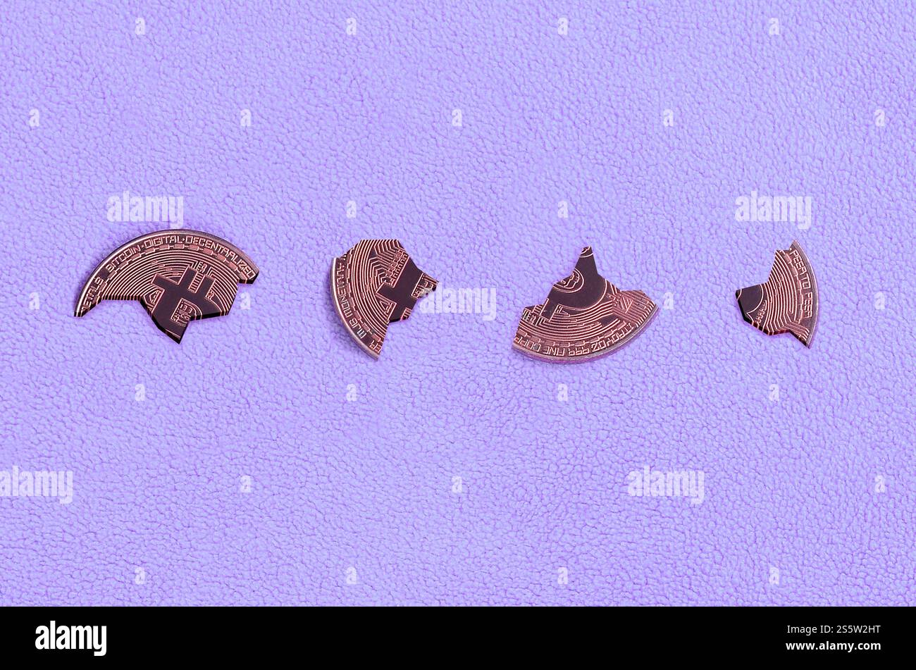 In Stücke zerbrochen Bitcoin auf einem violetten Vliesstoff-Hintergrund. Der Fall und der Zusammenbruch des Kurses der Kryptowährung. Schlechte Nachrichten für Stockfoto