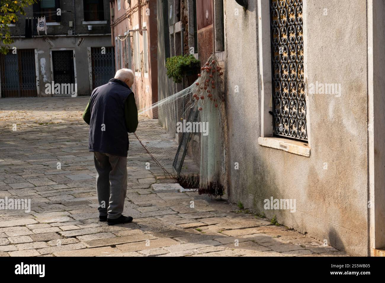 Ein alter Mann repariert einen Fischfang in der Nähe des Arsenale, Venedig, Italien Stockfoto