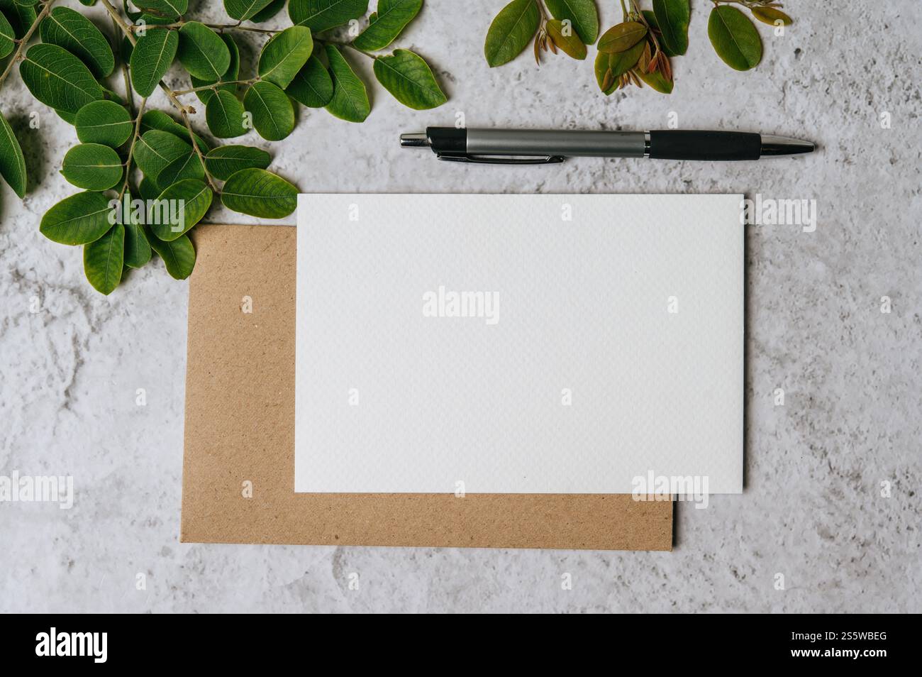 Eine leere Karte mit Umschlag, Stift und Blatt wird auf weißem Hintergrund platziert Stockfoto