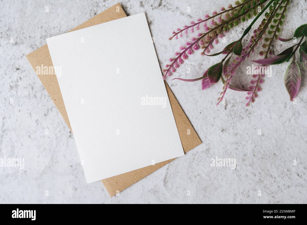 Eine leere Karte mit Umschlag und Blume ist auf weißem Hintergrund platziert Stockfoto