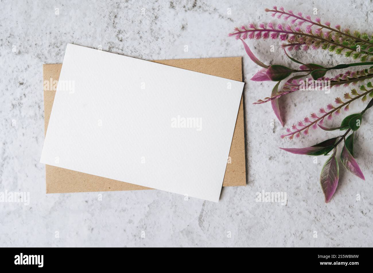 Eine leere Karte mit Umschlag und Blume ist auf weißem Hintergrund platziert Stockfoto