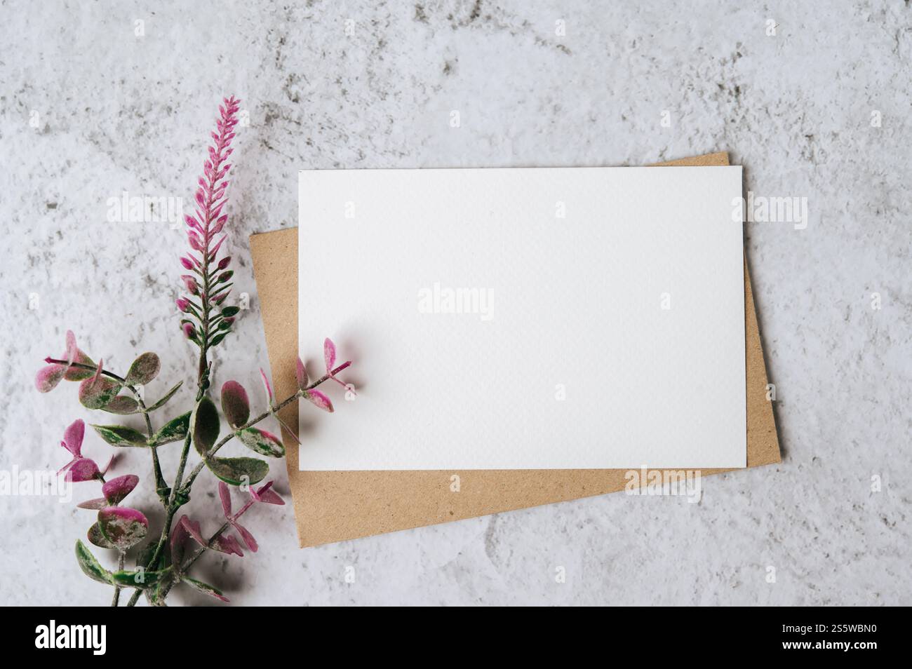 Eine leere Karte mit Umschlag und Blume ist auf weißem Hintergrund platziert Stockfoto