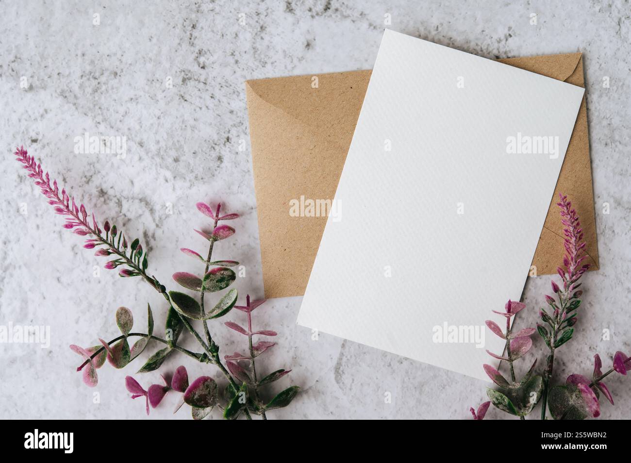 Eine leere Karte mit Umschlag und Blume ist auf weißem Hintergrund platziert Stockfoto