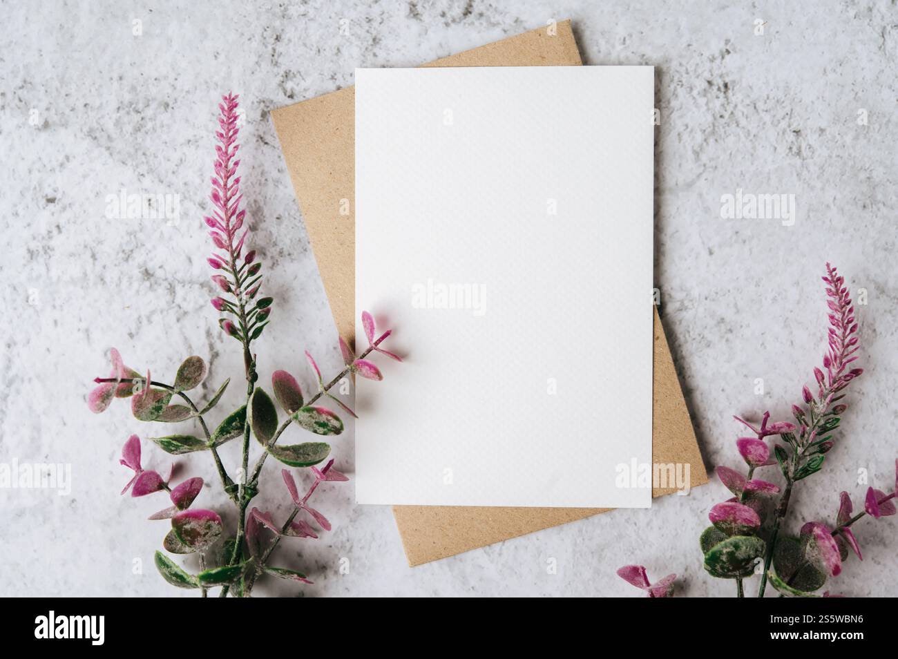 Eine leere Karte mit Umschlag und Blume ist auf weißem Hintergrund platziert Stockfoto