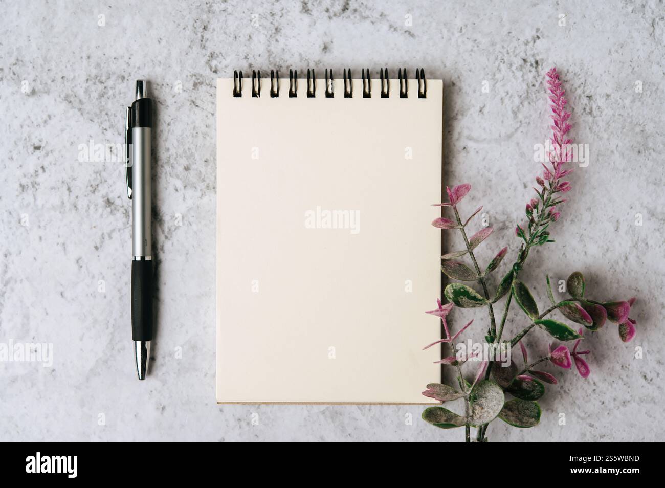 Ein Buch, ein Stift und eine Blume werden auf weißem Hintergrund platziert Stockfoto