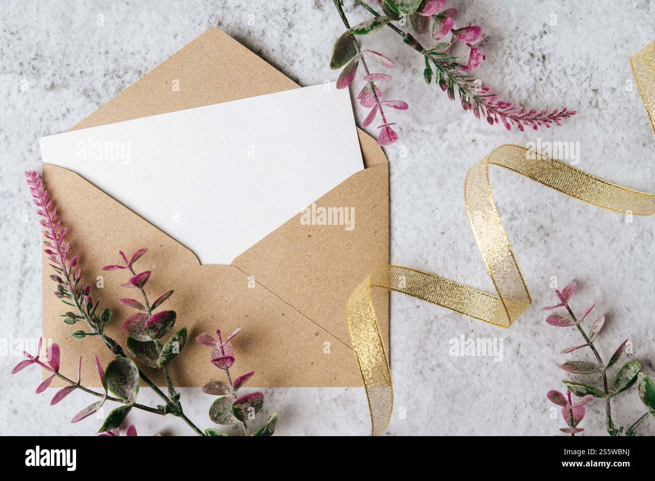 Eine leere Karte mit Umschlag und Blume ist auf weißem Hintergrund platziert Stockfoto