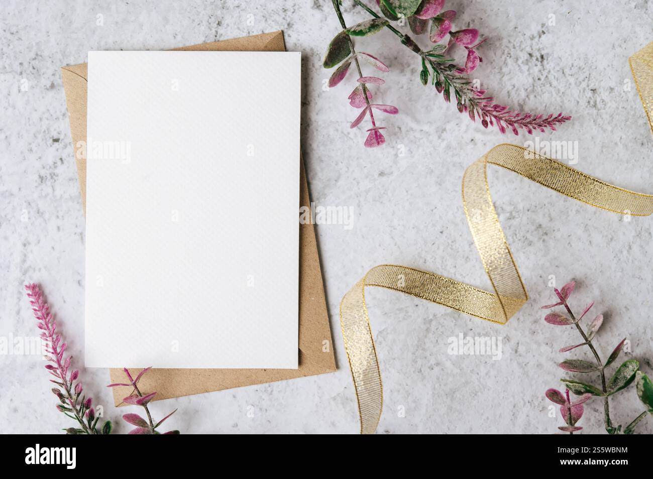 Eine leere Karte mit Umschlag und Blume ist auf weißem Hintergrund platziert Stockfoto