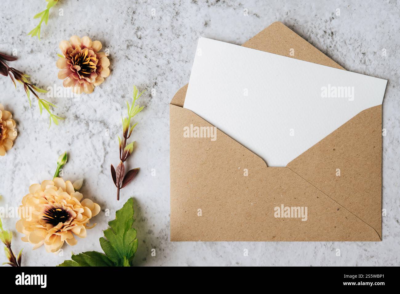 Eine leere Karte mit Umschlag und Blume ist auf weißem Hintergrund platziert Stockfoto