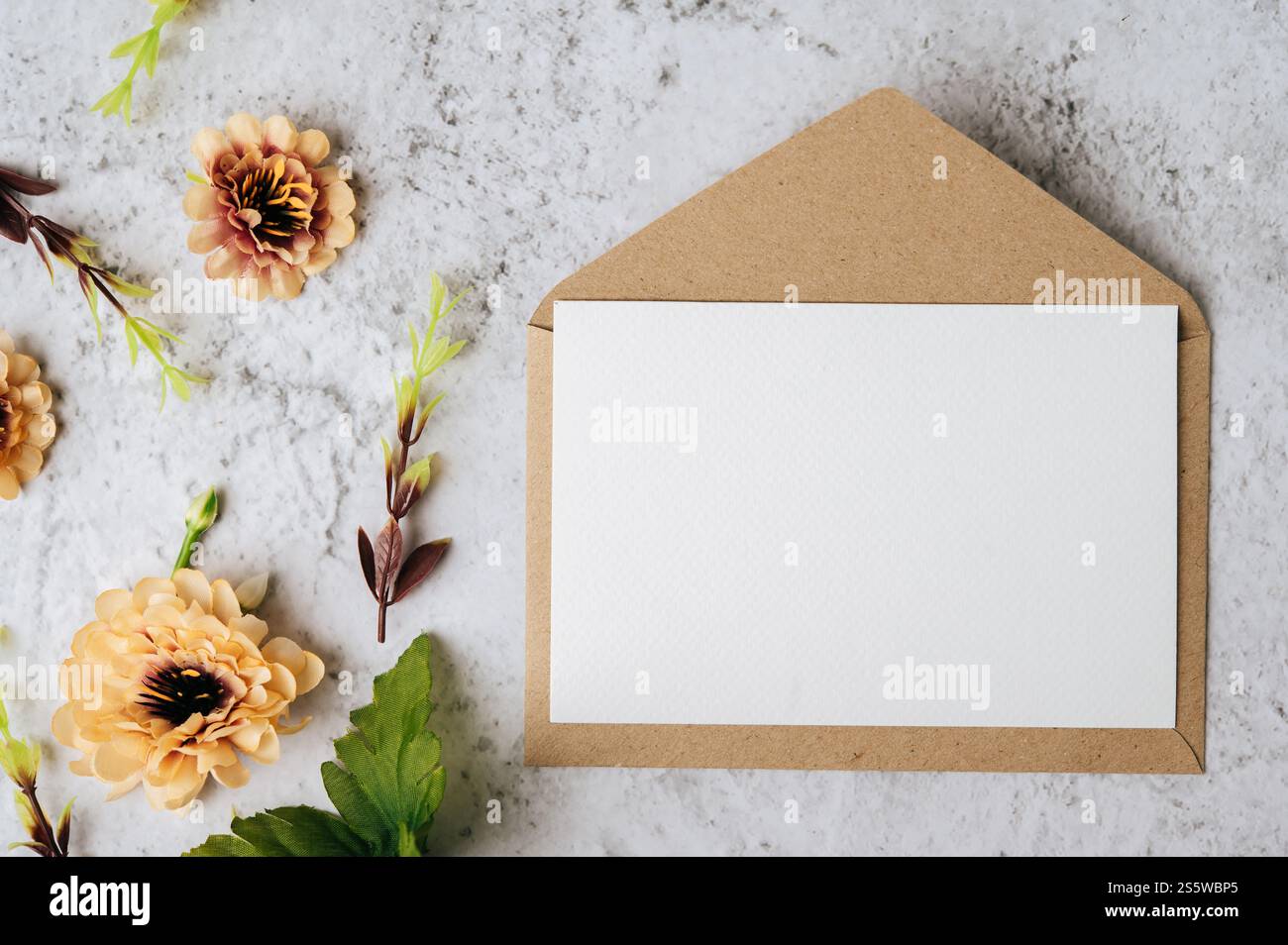 Eine leere Karte mit Umschlag und Blume ist auf weißem Hintergrund platziert Stockfoto