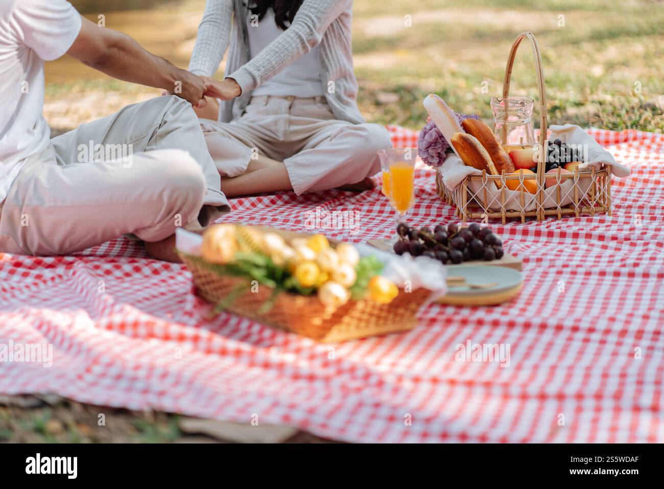 Verliebtes Paar genießt Picknickzeit im Park Outdoor Picknick. Glückliches Paar, das sich mit Picknickkorb entspannt. Stockfoto