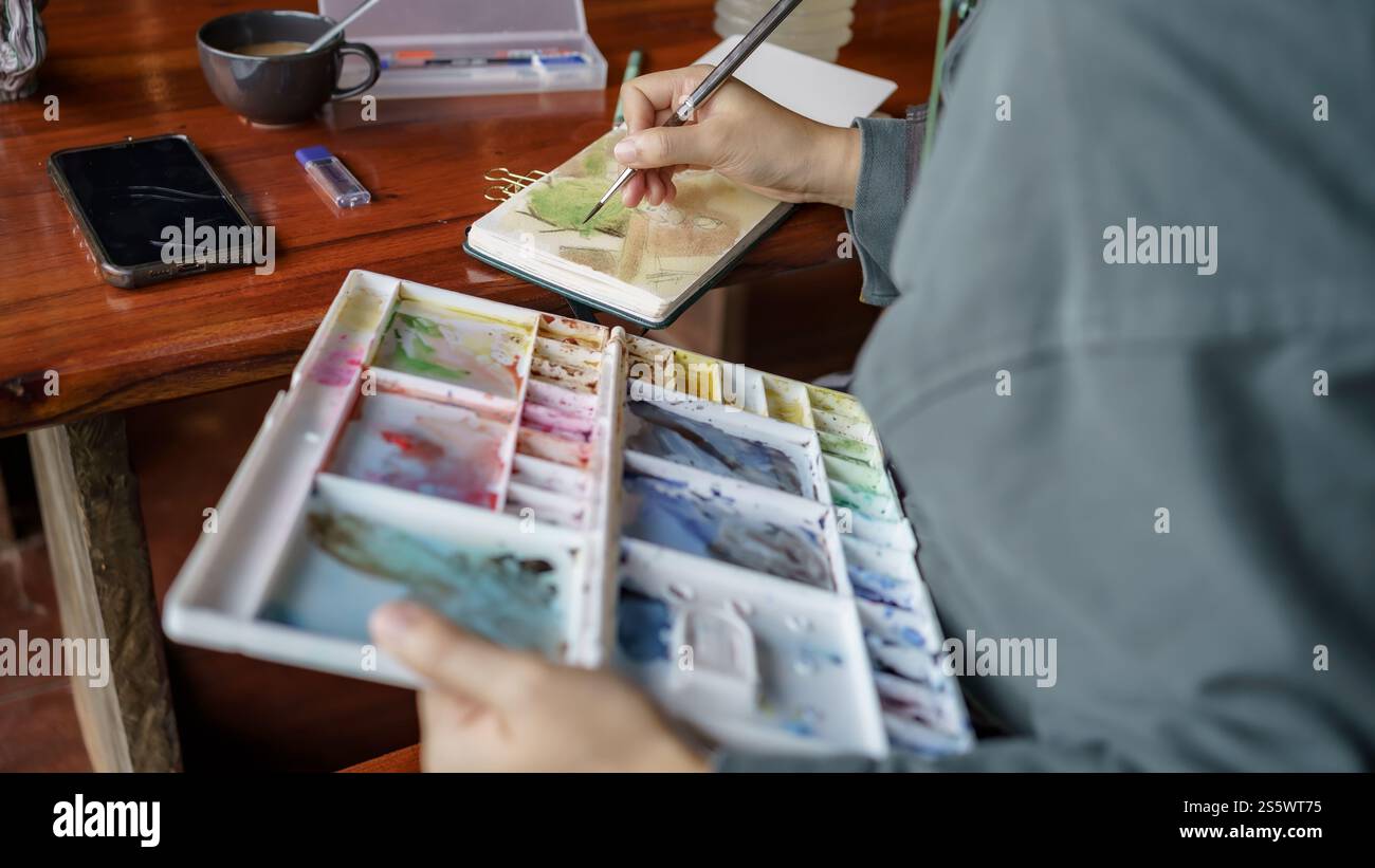 Student im Kunststudio. Hand haltender Künstler Pinsel mischen FarbÖlgemälde auf Palette Kunst Kreativität und Menschen Konzept. Stockfoto