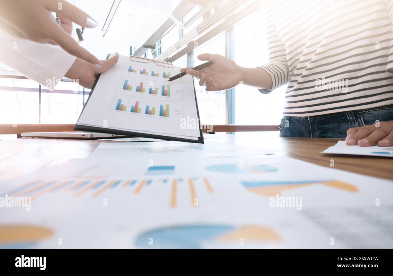Kreatives Team, das an einem Projekt im Loft Office arbeitet. Zwei Frauen diskutieren über Marketingplan. Laptop und Papierkram Stockfoto