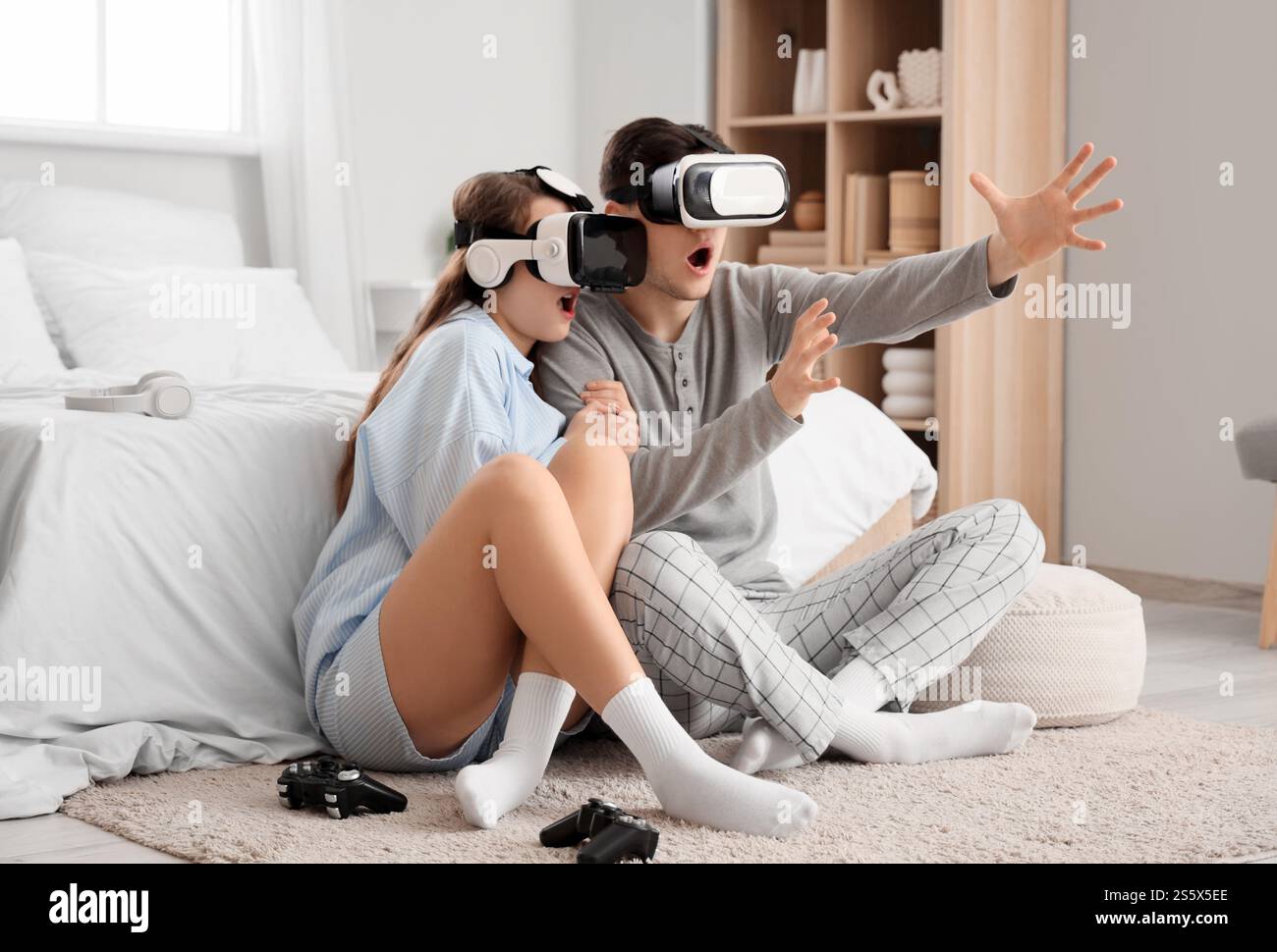 Verängstigte junge Paare mit VR-Brille im Schlafzimmer Stockfoto