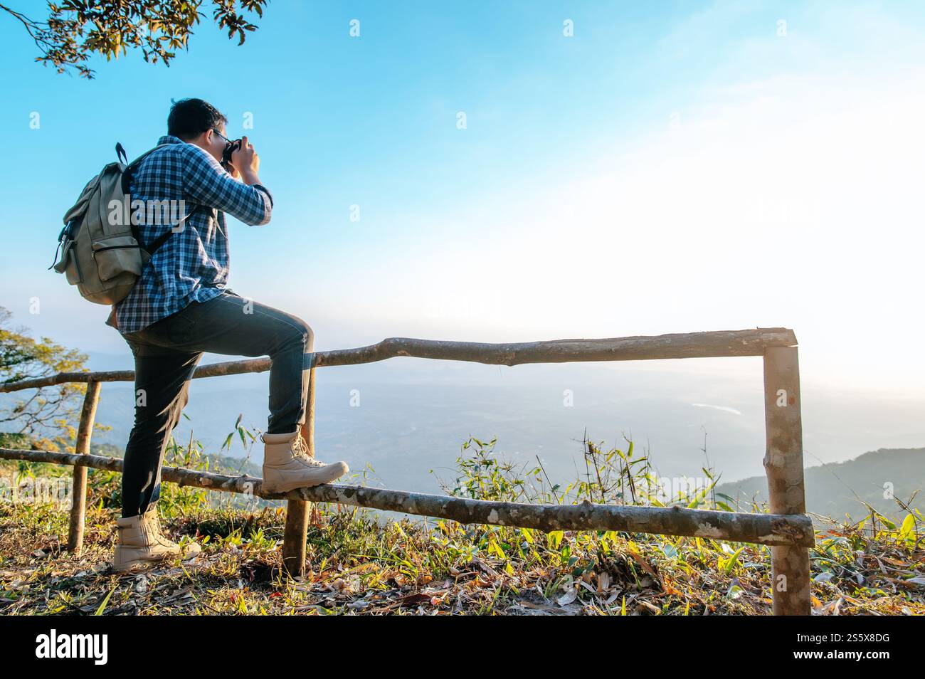 Junger asiatischer Wanderer und Rucksack machen mit der Kamera Fotos vom Aussichtspunkt im Wald. Kopierbereich Stockfoto