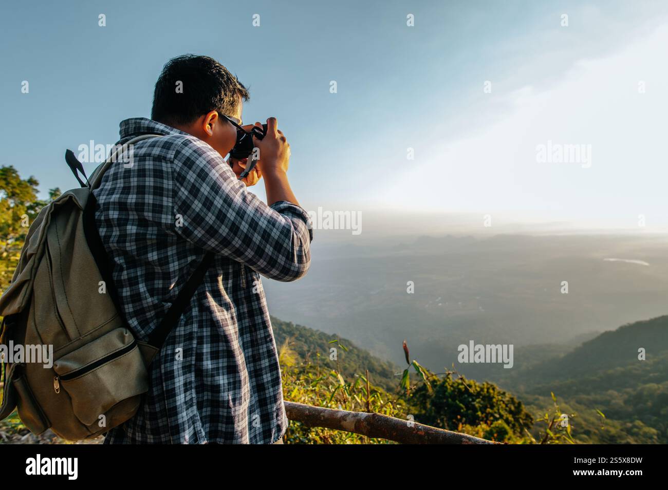 Junger asiatischer Wanderer und Rucksack machen mit der Kamera Fotos vom Aussichtspunkt im Wald. Kopierbereich Stockfoto