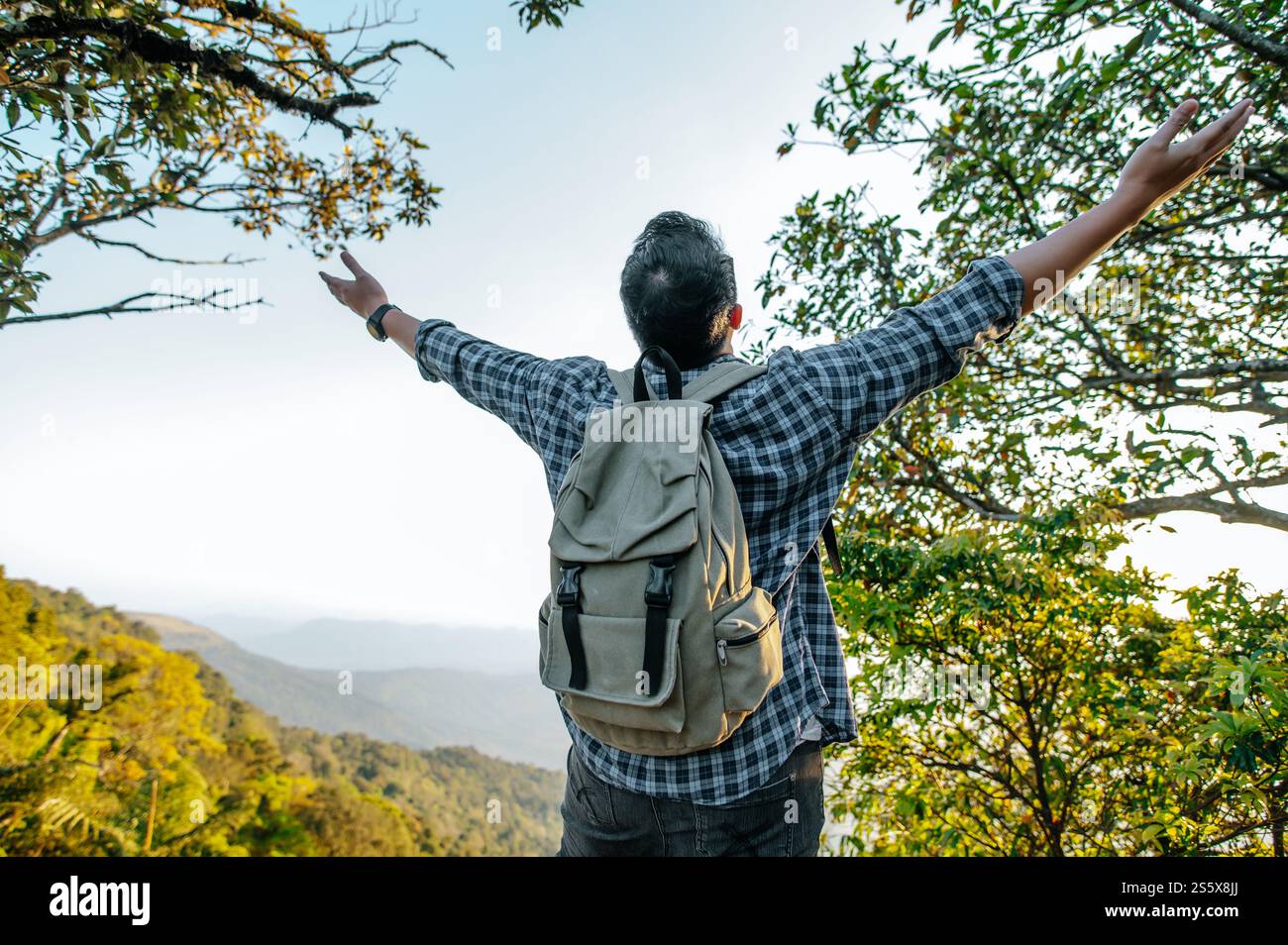 Rückansicht der Rückseite des jungen asiatischen Wanderers stehend und mit Happy-up-Händen auf dem Gipfel des felsigen Berges, Kopierraum Stockfoto