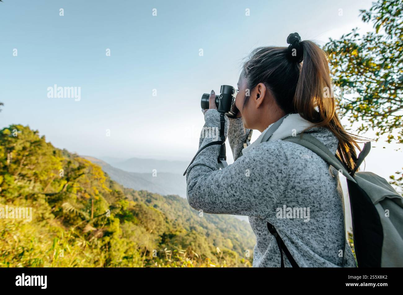 Junge asiatische Wanderer und Rucksack nutzen Kamera, um Fotos im Wald zu machen. Kopierbereich Stockfoto
