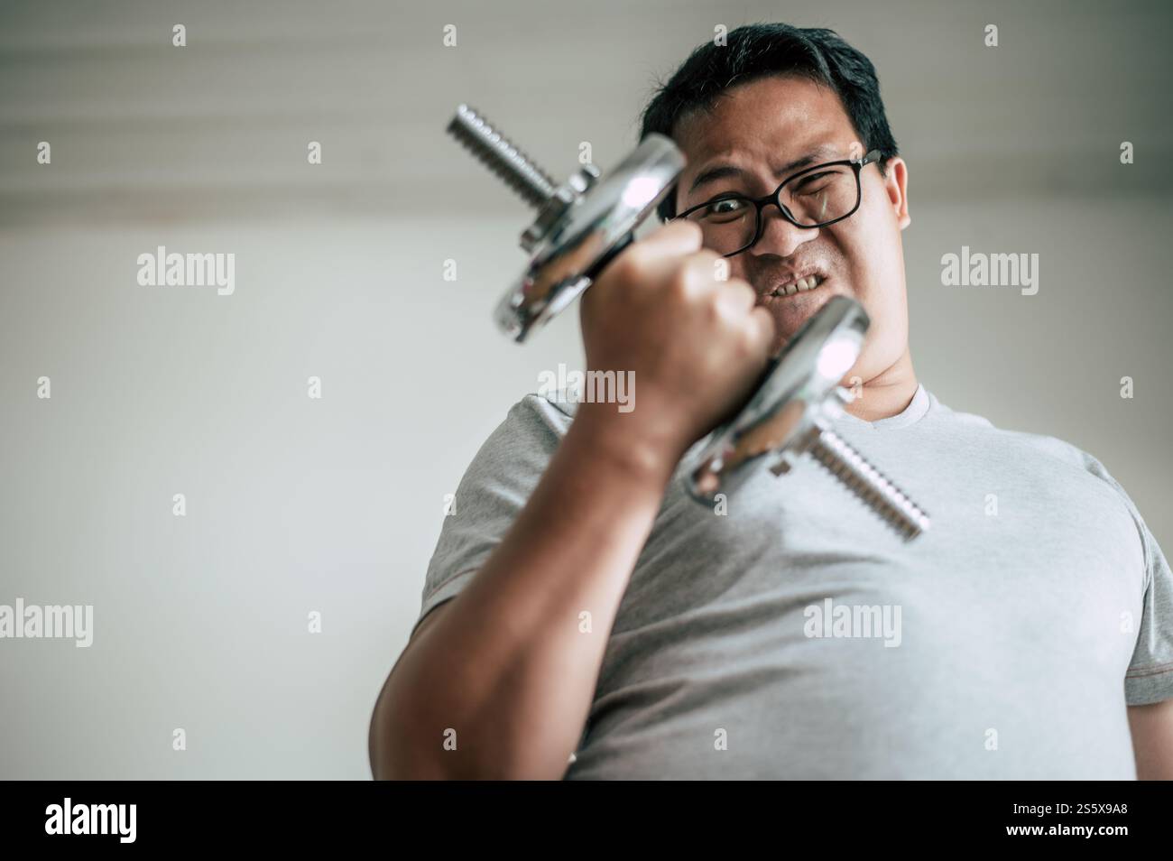 Lustiger fette Mann in der Brille hebt Hantel auf, um für gesunde, Kopierraum zu trainieren Stockfoto