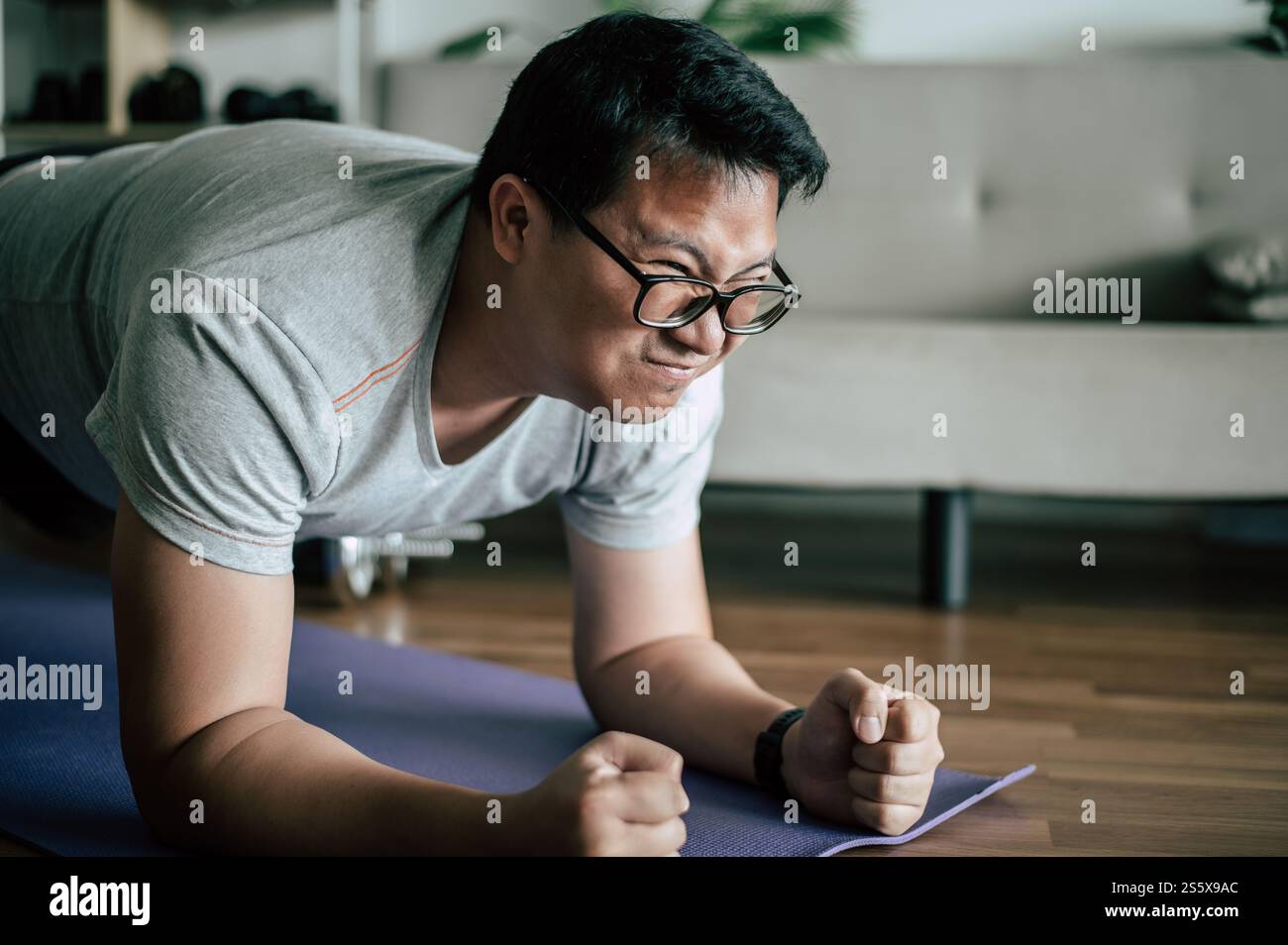 Lustiger übergewichtiger Mann in Brille versucht, auf den Boden zu beplanken, beim Training, beim Kopieren Stockfoto
