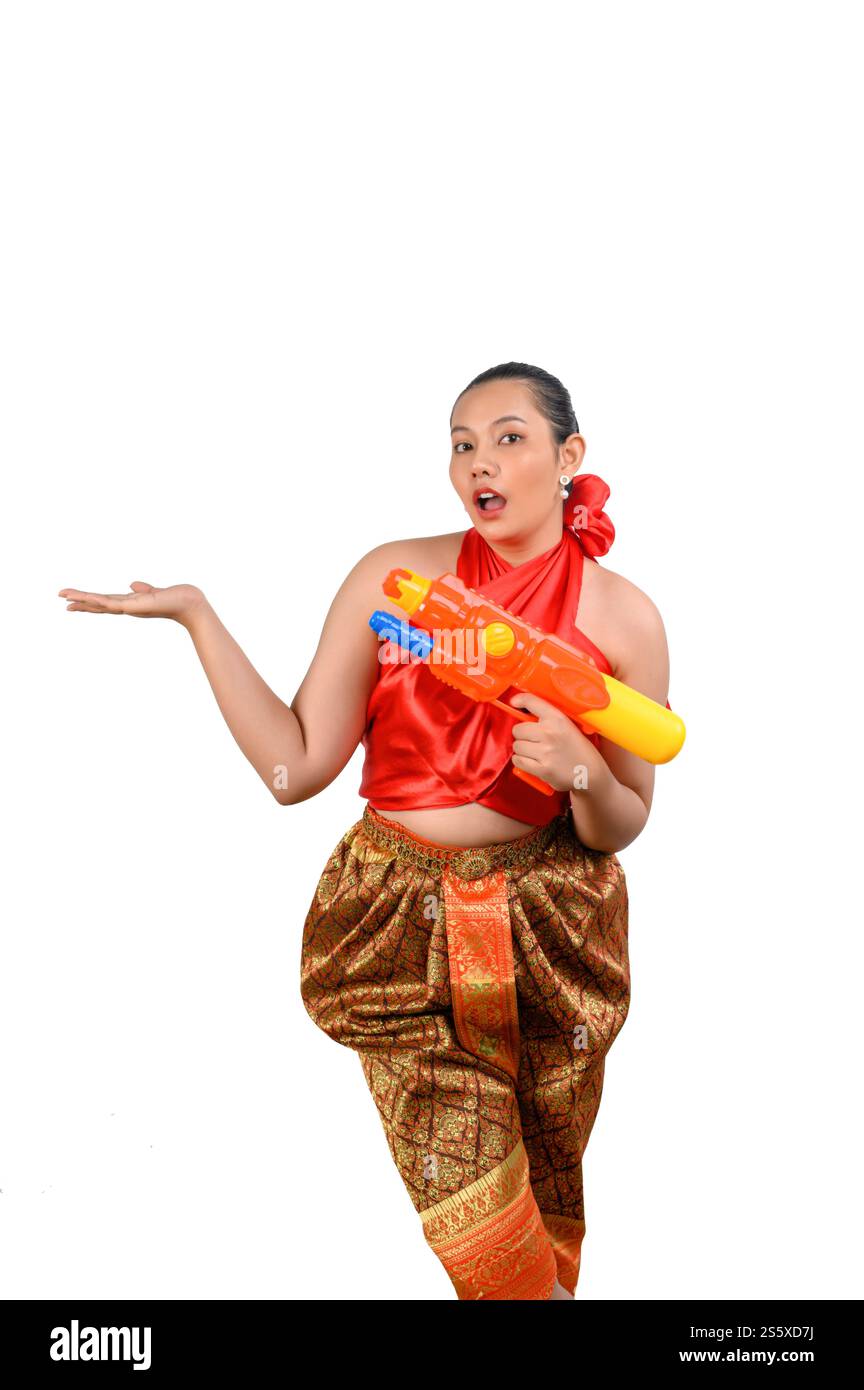 Porträt schöne Frau im Songkran Festival mit traditioneller thailändischer Tracht stehend und mit Wasserpistole mit Lächeln und Kamera auf weiß Stockfoto