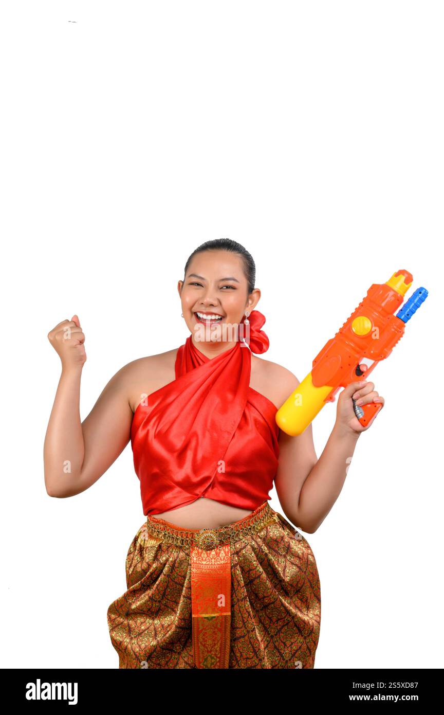 Porträt schöne Frau im Songkran Festival mit traditioneller thailändischer Tracht stehend und mit Wasserpistole mit Lächeln und Kamera auf weiß Stockfoto