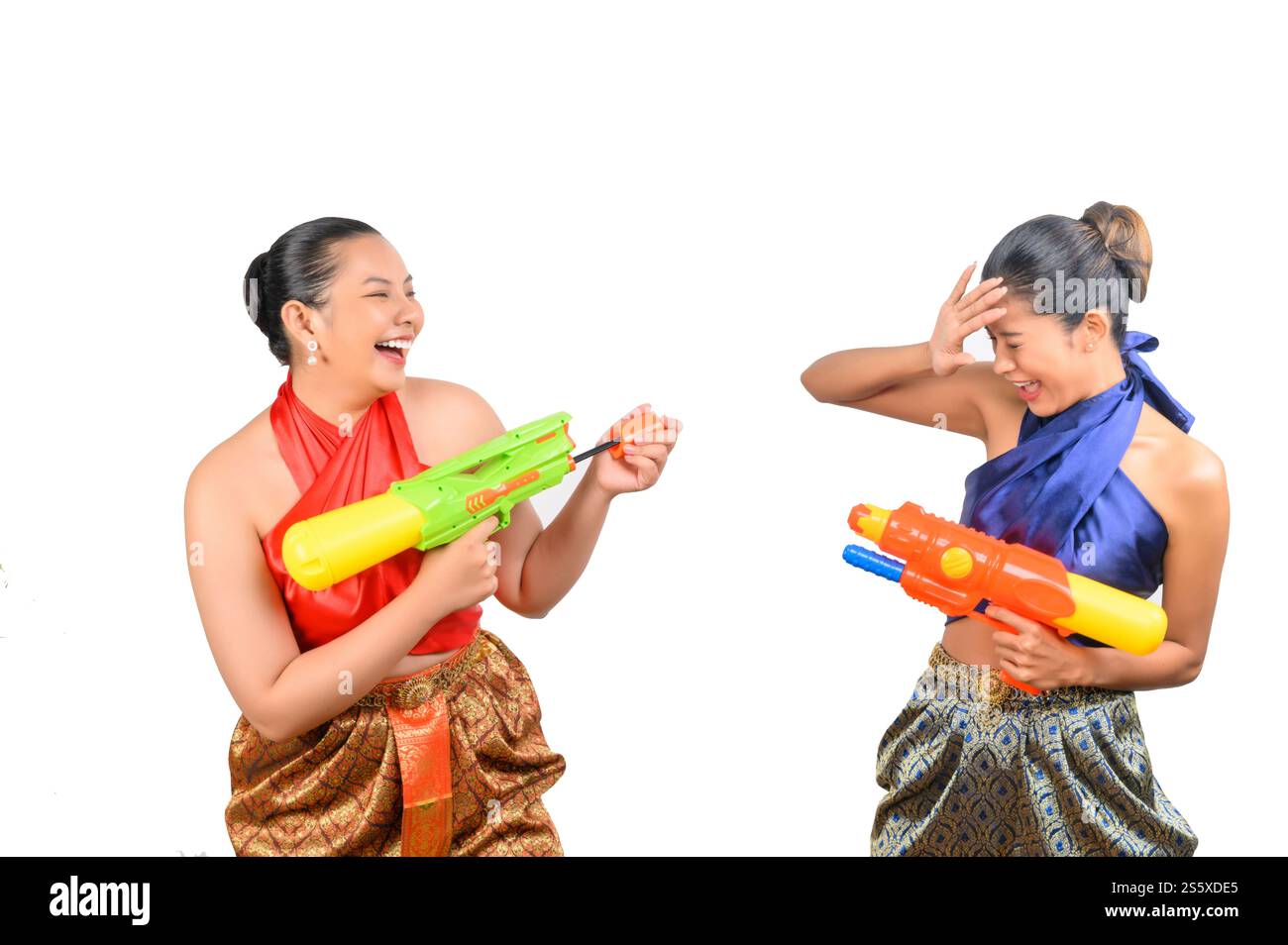 Porträt schöne Frau im Songkran Festival mit traditioneller thailändischer Tracht stehend und mit Wasserpistole mit Lächeln und Lachen mit Spaß auf weiß Stockfoto