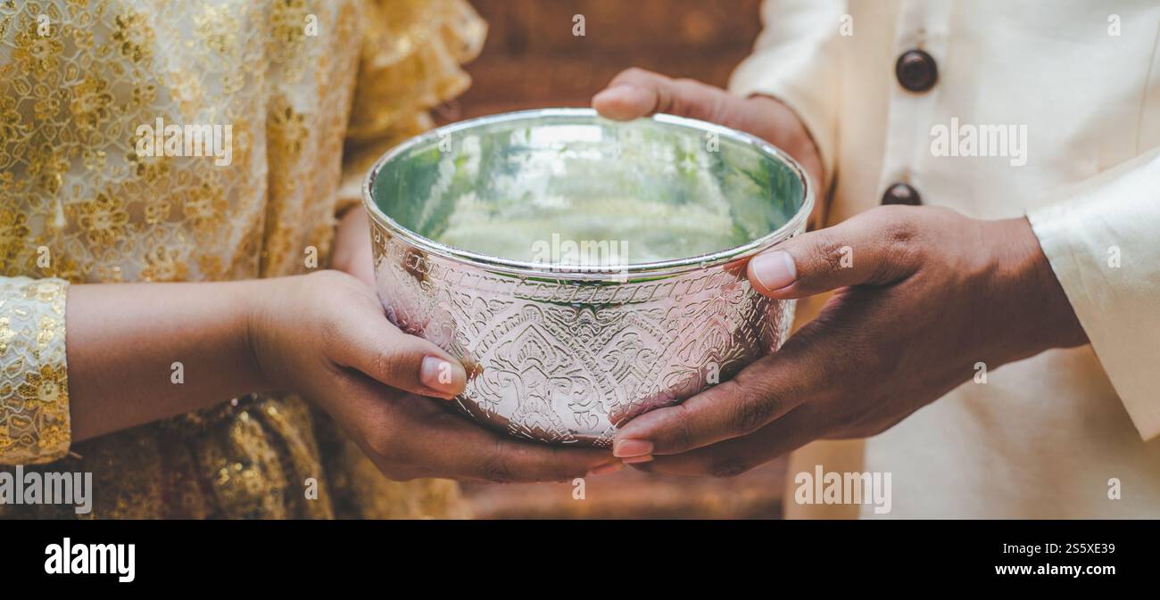 Junger Mann und Frau in wunderschönen thailändischen Kostümen, die eine Wasserschale halten und im Tempel stehen und die gute Kultur der thailändischen Menschen bewahren Stockfoto