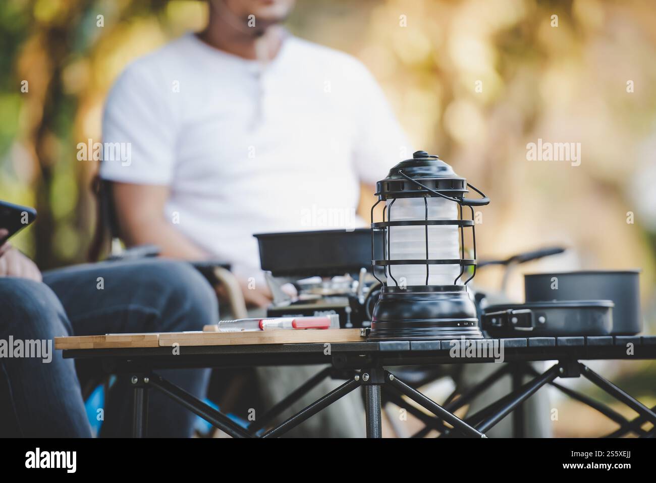 Nahaufnahme der Campingausrüstung mit Menschenkunde. Kochset vorne. Outdoor-Küche, Reisen, Camping, Lifestyle-Konzept. Stockfoto