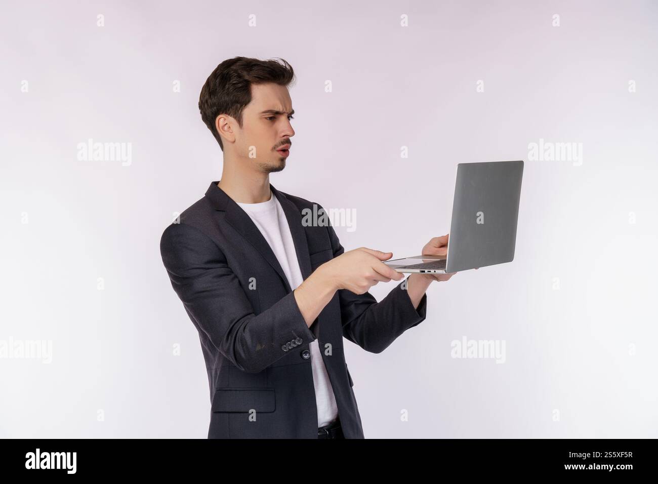 Porträt eines jungen Geschäftsmannes hat Computerprobleme und hält einen Laptop isoliert auf weißem Hintergrund. Technologie und Geschäftskonzept. Stockfoto