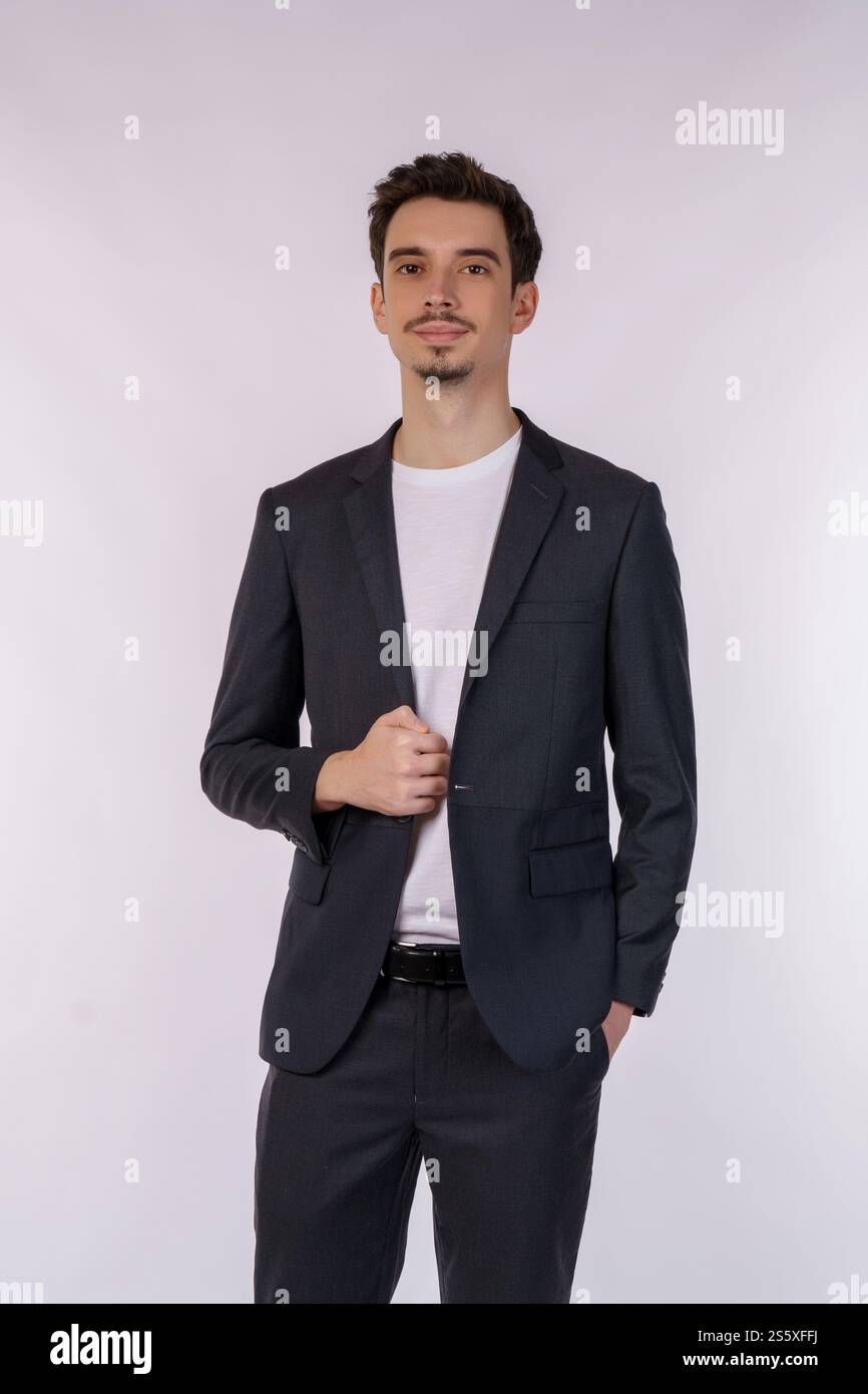 Porträt eines glücklichen, gutaussehenden jungen Mannes im Anzug, der auf isoliertem Hintergrund posiert. Stockfoto