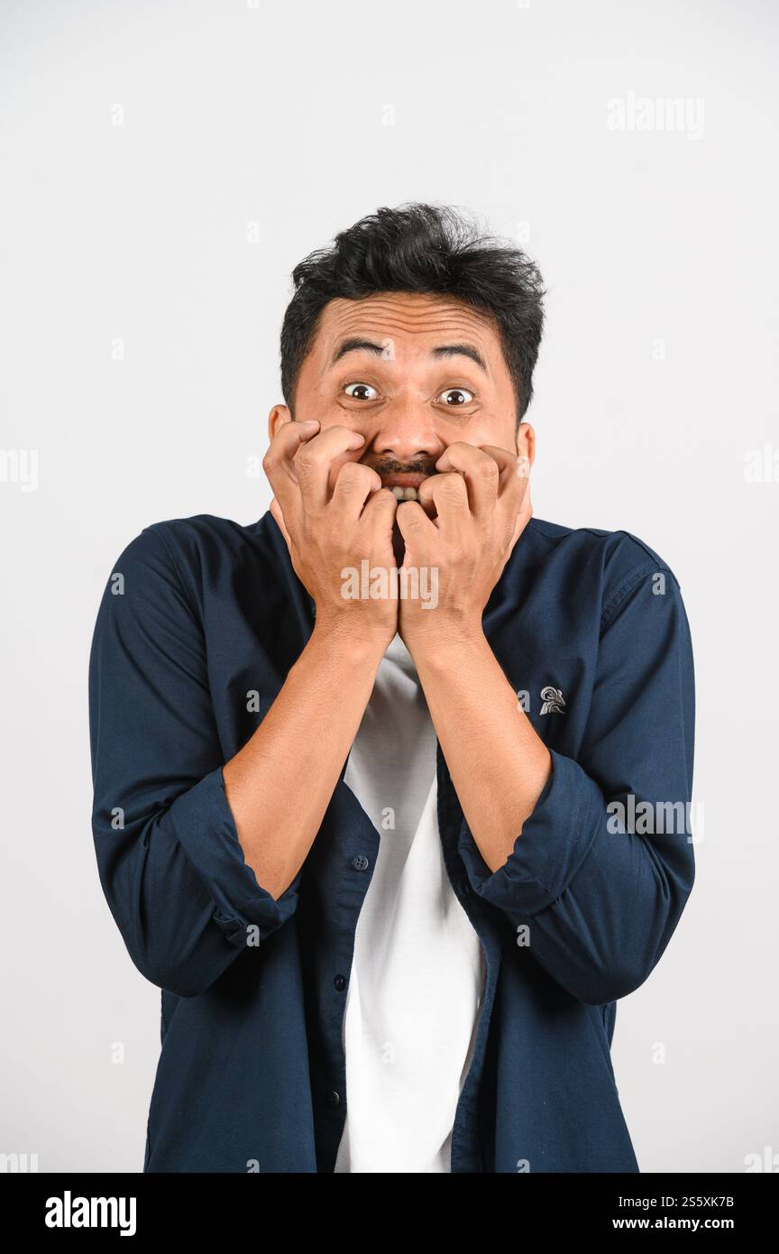 Porträt eines verängstigten jungen asiatischen Mannes in blauem Hemd, der eine nervöse Geste auf weißem Hintergrund macht. Ausdruck und Lifestyle-Konzept. Stockfoto