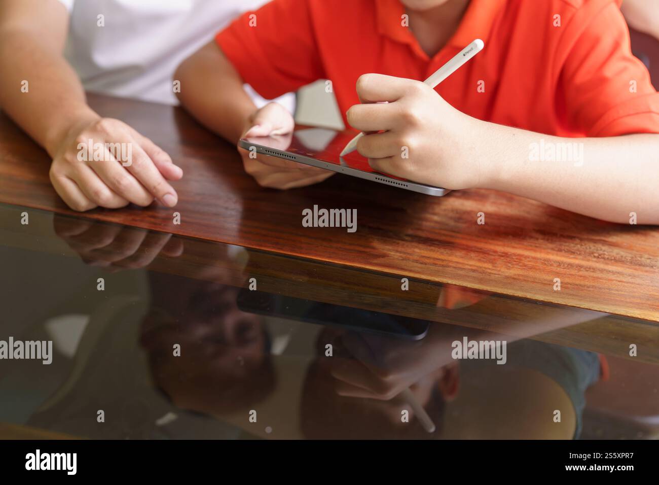 Asiatischer Vater und Sohn mit Tablet lernen Son das Drawplay mit dem digitalen Tablet am Schreibtisch zu lernen Vaterschaftskonzept Stockfoto