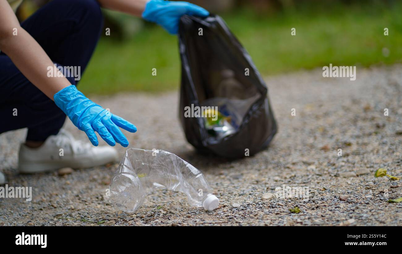 Ehrenamtliche Wohltätigkeitsfrau Hand hält Müll schwarze Tasche und Plastikflaschenmüll für das Recycling für die Reinigung im Park Freiwilligenkonzept Wiederverwendung und Stockfoto