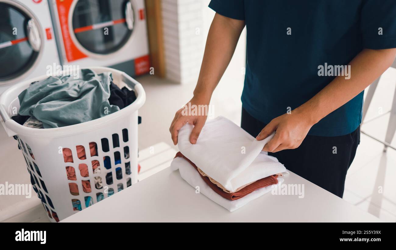 Hausmann mit Korb und schmutziger Wäsche gewaschene Kleidung im Waschraum. Waschmaschine im Wäschereigeschäft Konzept Stockfoto