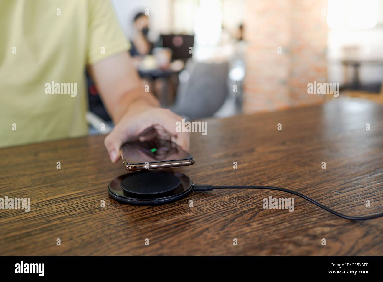 Laden des Mobiltelefonakkus mit dem drahtlosen Gerät in der Tabelle. Smartphone wird auf einem Ladepad aufgeladen. Mobiltelefon in der Nähe des kabellosen Ladegeräts Stockfoto