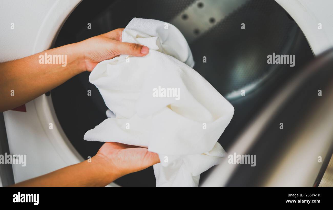 Hausmann mit Korb und schmutziger Wäsche gewaschene Kleidung im Waschraum. Waschmaschine im Wäschereigeschäft Konzept Stockfoto