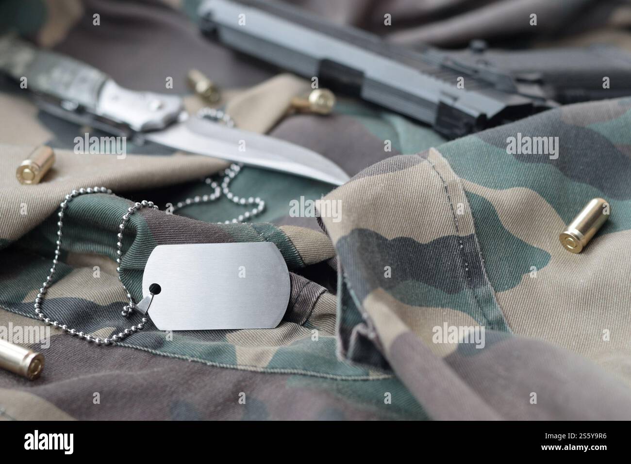 Army Dog Tag Token mit 9-mm-Kugeln und Pistole liegen auf gefaltetem grünen Stoff. Ein Set von Militärveteranen oder ein altes Trophäenkit. Armee Stockfoto