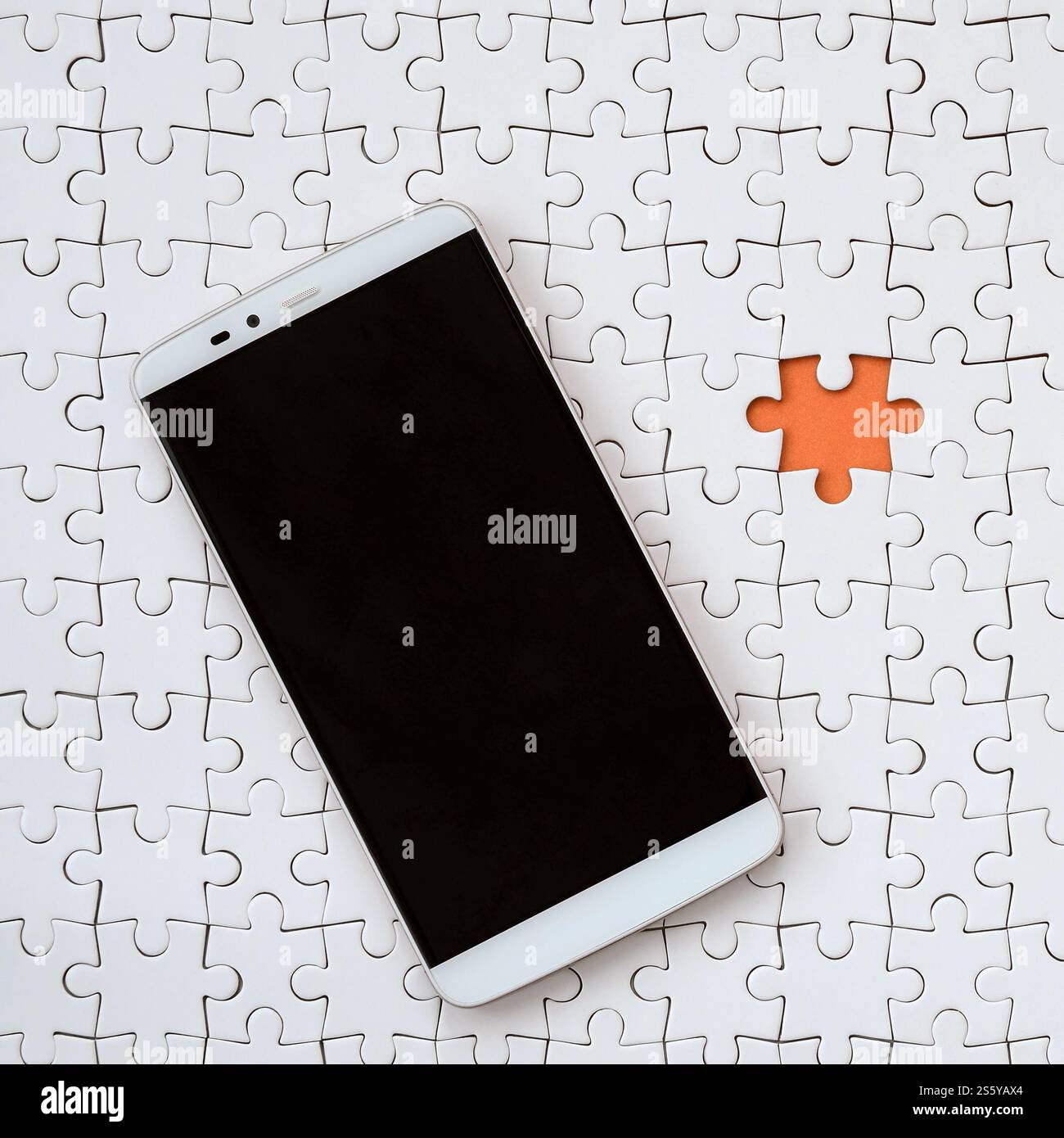 Eine moderne grosse Smartphone mit Touchscreen liegt auf einem weißen Puzzle im zusammengebauten Zustand Stockfoto