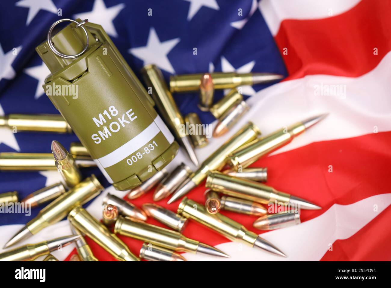M18 Rauchgranate und viele gelbe Kugeln und Patronen auf US-Flagge. Konzept des Waffenhandels auf US-Territorium oder Sondereinsätzen. Stockfoto