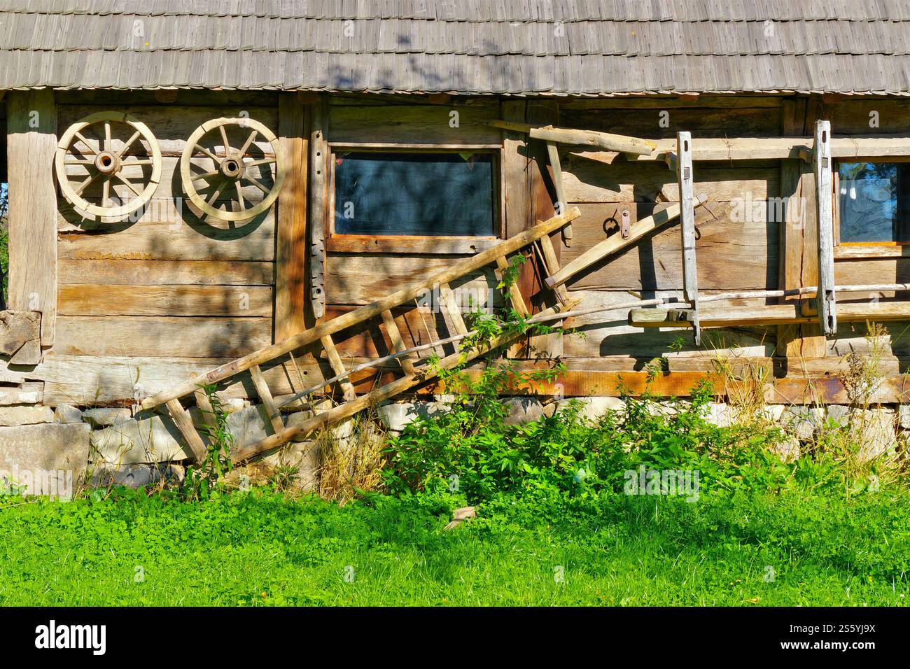 Viele alte Feldwerkzeuge auf einer Holzscheune Stockfoto