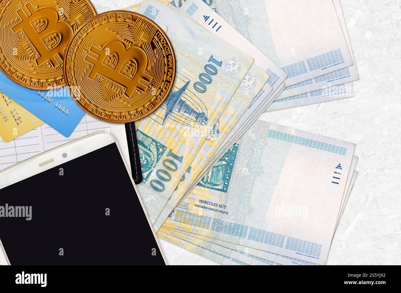 1000 ungarische Forint-Scheine und goldene Bitcoins mit Smartphone und Kreditkarten. Anlagekonzept für Kryptowährungen. Krypto-Mining oder -Handel Stockfoto