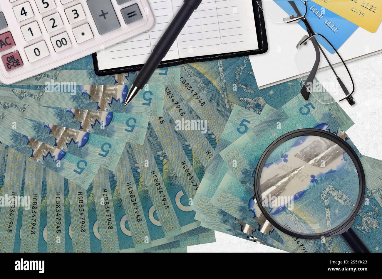5 kanadische Dollarscheine und Taschenrechner mit Brille und Stift. Steuerzahlungssaisonkonzept oder Investitionslösungen. Job mit hohem Gehalt wird gesucht Stockfoto