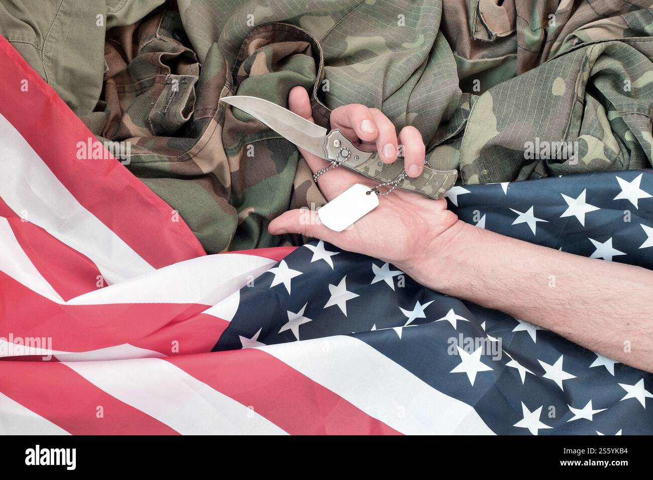 Hundemarken liegen bei der Hand eines Menschen, der Selbstmord mit einem Messer begeht. Das Konzept eines Veteranen, der den Schmerz nicht länger ertragen kann, beschließt, sich umzubringen. Hund Stockfoto
