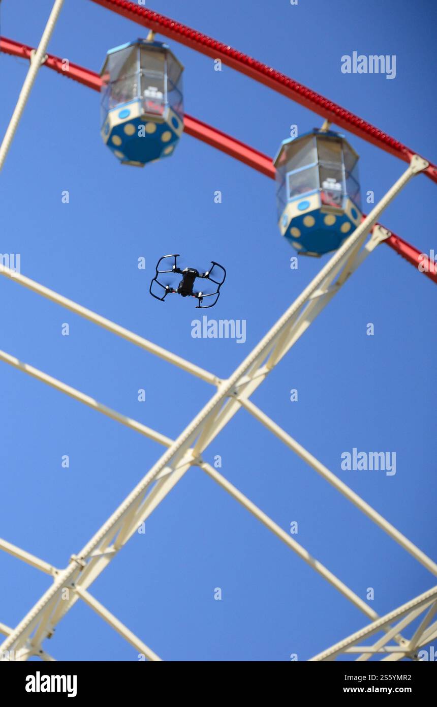 Drohne mit Fotokamera startet vom Land und fliegt für Fotos vor dem Riesenrad. Die Drohne startet vom Land und fliegt, um Fotos zu machen Stockfoto