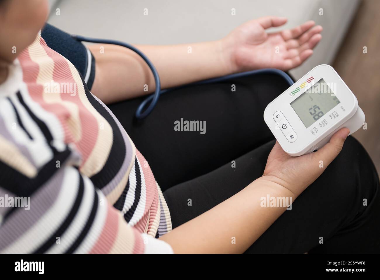 Übergewichtige Frauen plus Größe Selbstkontrollen Blutdruck und Herzfrequenztonometer Selbstkontrolle zu Hause. Stockfoto