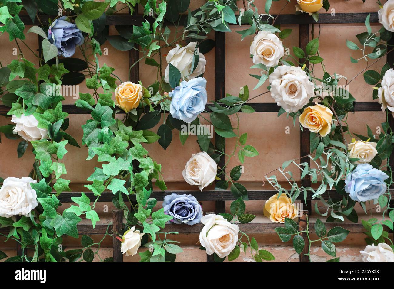Dekoration urbanes Kunstobjekt aus farbenfrohen, eleganten Blumen auf Holzgitter an der Wand. Dekoration urbanes Kunstobjekt aus farbenfrohen, eleganten Blumen an der Wand Stockfoto